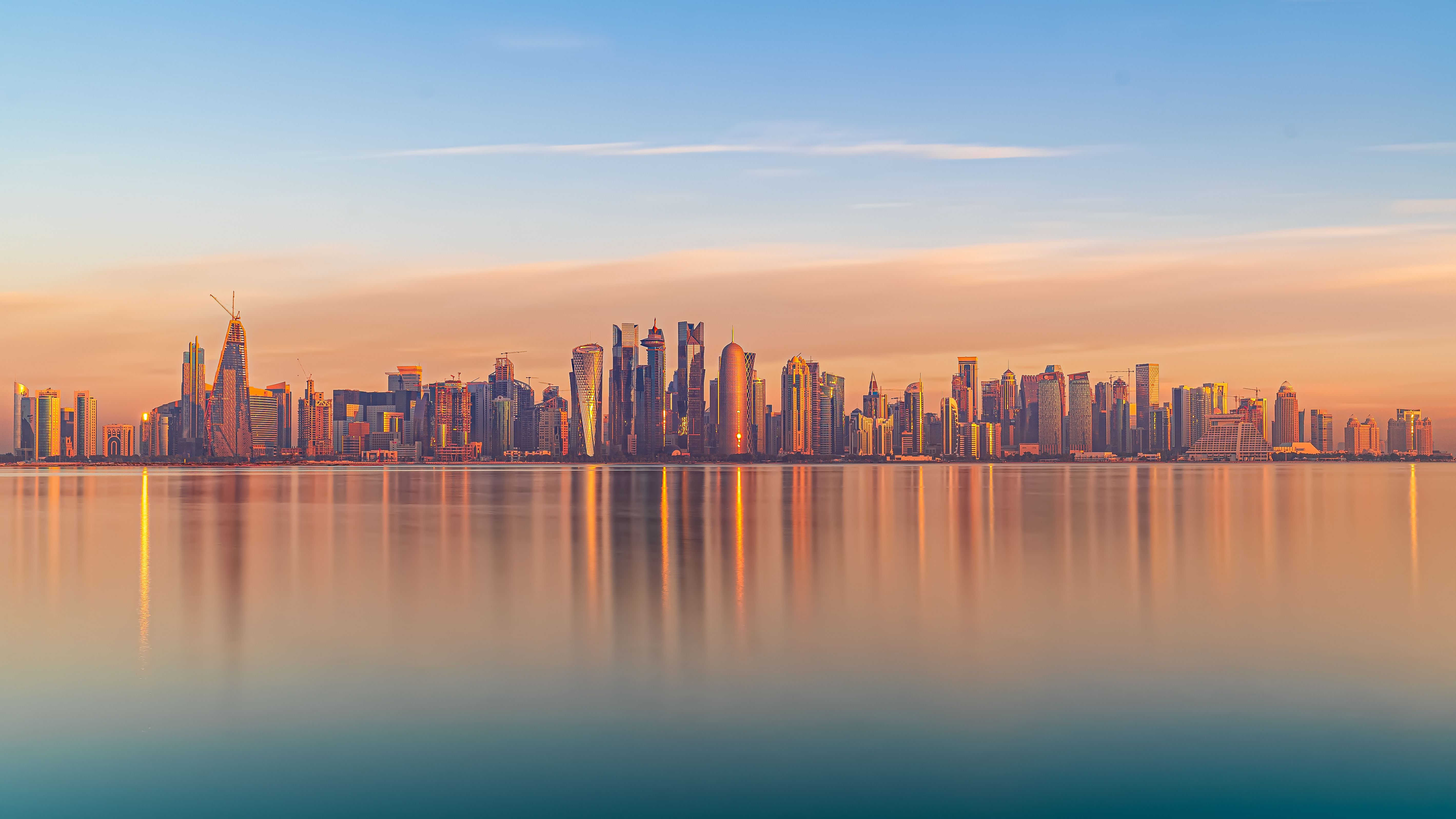 Modern city skyline reflected over calm water at golden hour