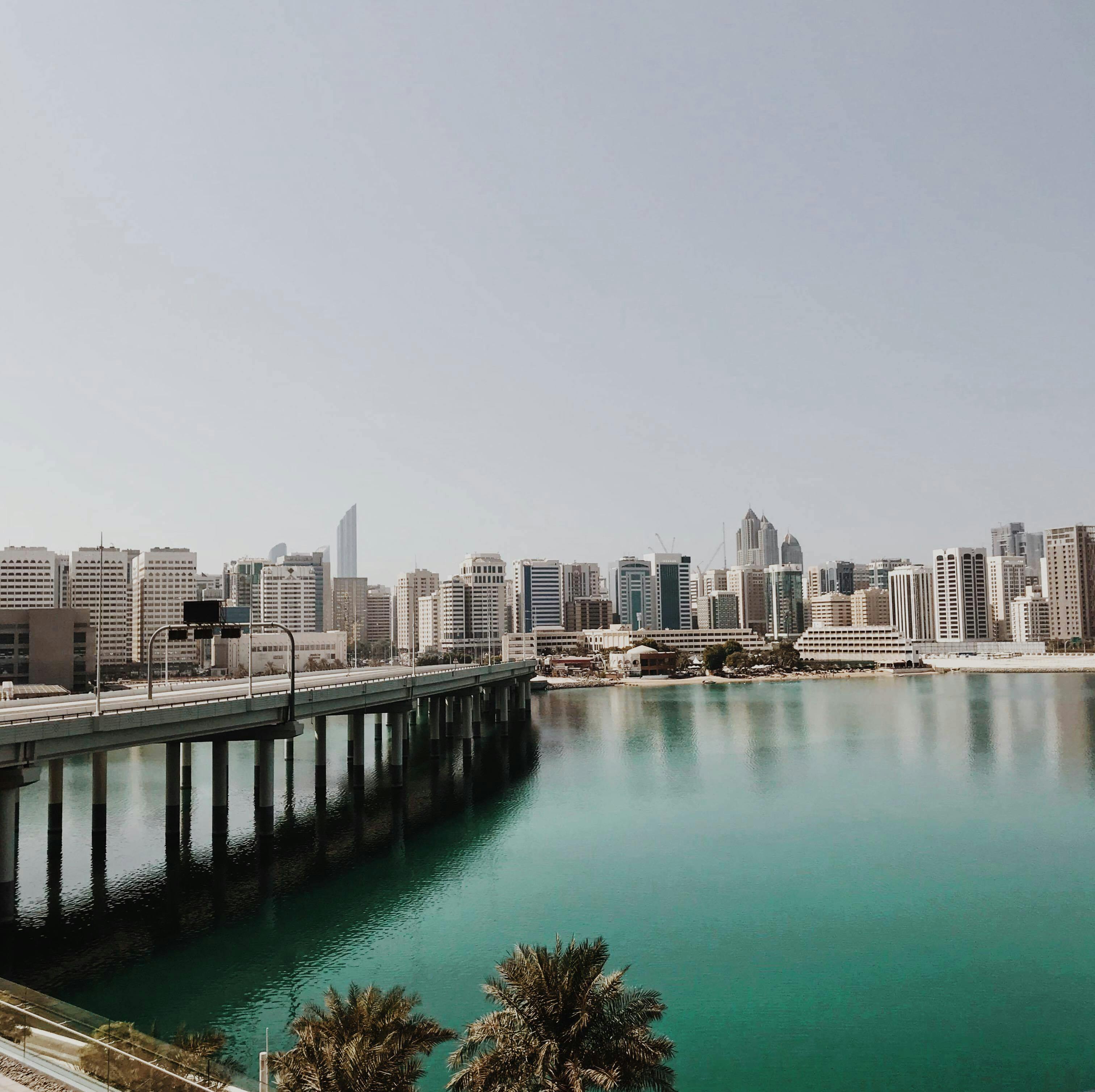Abu Dhabi skyline across calm water, with the Sheikh Khalifa Bridge